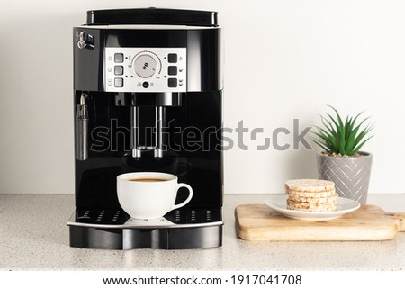 Modern espresso coffee machine with a cup in interior of kitchen closeup. Royalty-Free Stock Photo #1917041708