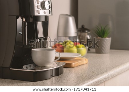 Modern espresso coffee machine with a cup in interior of kitchen closeup. Royalty-Free Stock Photo #1917041711