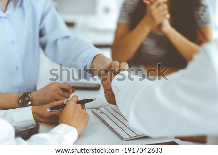 Two businessmen are shaking hands in office while sitting at the desk, close-up. Colleagues applauding of success meeting end. Business people concept Royalty-Free Stock Photo #1917042683