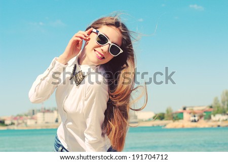 Happy young hipster girl in sunglasses walking on the beach in the summer. Outdoors, lifestyle. Shot retro colors. Photo toned style instagram filters