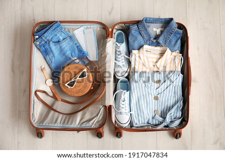 Open packed suitcase on wooden background Royalty-Free Stock Photo #1917047834