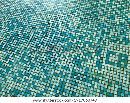 An abstract mosaic on the ground of a pool with blue tiles