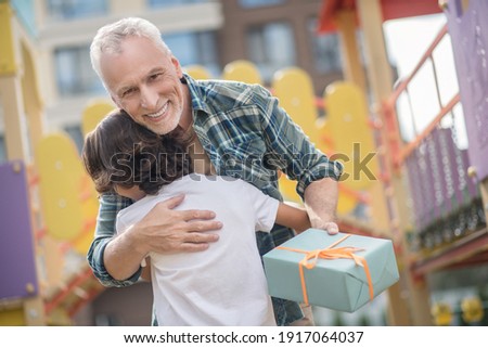 Happy day. Happy father giving a gift to his son and both looking excited
