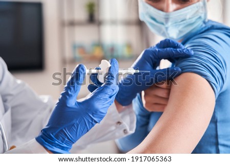 Doctor making vaccination to blonde woman patient. Female doctor vaccinating caucasian woman. Close-up of female doctor injecting female patient with syringe to protect of coronavirus infection. Stock Royalty-Free Stock Photo #1917065363
