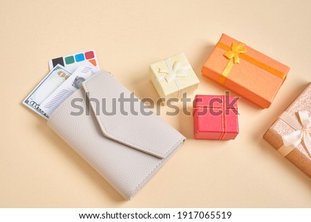 wallet, credit card, money and small boxes gifts on beige background, gift purchase concept