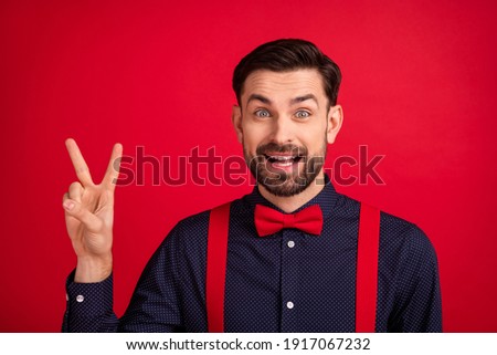 Photo of young handsome positive cheerful excited gentleman showing v-sign greetings isolated on red color background