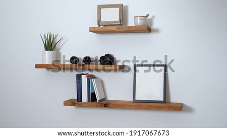 minimalist floating shelf made of wood with books and a picture on it Royalty-Free Stock Photo #1917067673