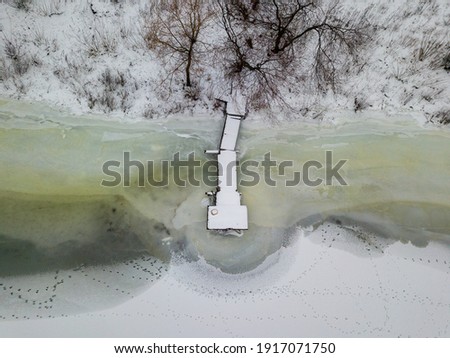 Frozen snow-covered pier on the shore. Aerial drone view. Frosty winter morning.