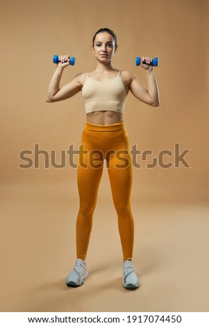 Beautiful fit young woman doing exercise with dumbbells