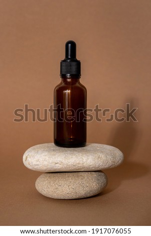 Brown glass bottles of cosmetic products on stone on beige paper background. Natura Spa Cosmetic Beauty concept. High quality photo