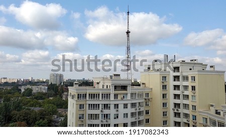 Cumulus clouds over city buildings and communication tower antenna in residential district of European city