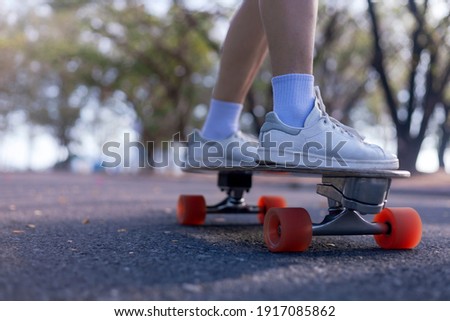 Close-up Asian women surf skate or skateboard outdoors on beautiful morning. women play surf skate at park on morning time. Close up Asian women leg wear sneaker paly surf skate on public park. Sport  Royalty-Free Stock Photo #1917085862