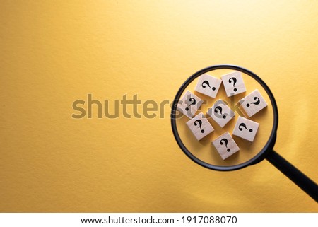 Focus on Question Mark symbol on a wooden tiles using magnifying glass against yellow background. Concept of Q and A, questions and faq Royalty-Free Stock Photo #1917088070