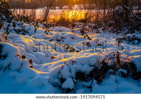 sunset over the snow in front of the lake