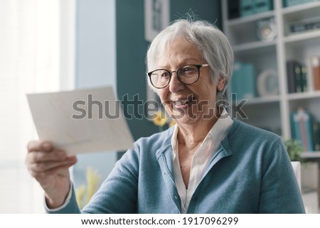 Happy senior woman holding a picture and smiling