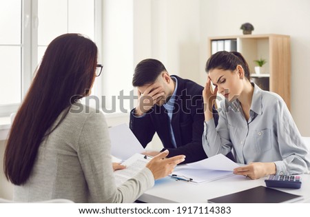Financial problems. Couple getting very bad news from real estate agent, bank manager or lawyer. Sad clients reading bankruptcy notice or mortgage contract with disadvantageous terms and conditions Royalty-Free Stock Photo #1917114383