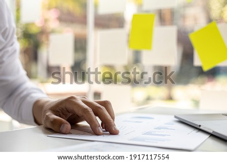 Close-up of a businessman's hand on a company finance document, a businessman examining the financial data from a company finance chart. Financial concept.