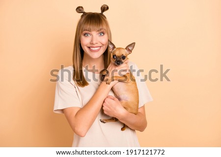 Photo portrait of smiling girl holding little chihuahua dog pet isolated on pastel beige color background