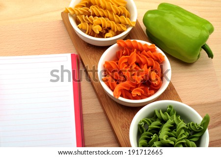 Pasta with blank recipe book and green paprtika 