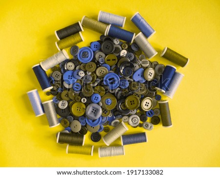 Collection of yarn on spool and sewing buttons on yellow background. Trendy color 2021. Sewing, tailor tools and  hobby pattern. Background or templates of crafts and dress making. Copy space for text