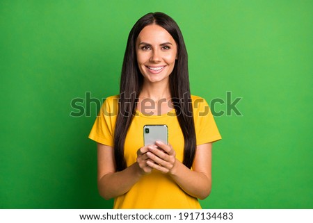Photo of attractive cheerful young woman hold phone good mood isolated on vivid green color background