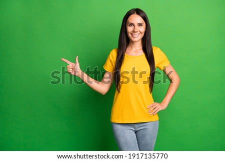 Photo of young attractive girl happy smile point finger empty space ad promo choice choose isolated over green color background