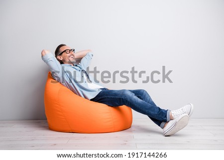 Full body profile side photo of man happy positive smile sit bag rest relax look empty space isolated over grey color background