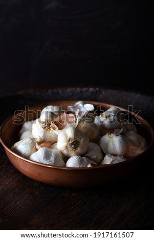 Garlic Cloves and Bulb in metal bowl on dark wooden background.