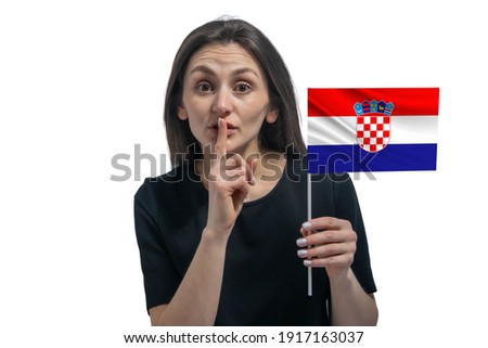 Happy young white woman holding flag of Croatia and holds a finger to her lips isolated on a white background.