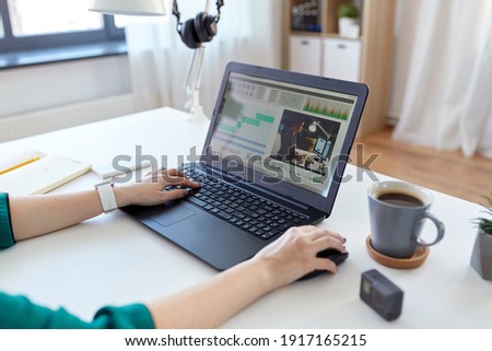 technology, post production and vlog concept - close up of woman working in video editor program on laptop computer working at home office