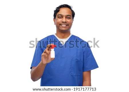 medicine, profession and healthcare concept - happy smiling indian doctor or male nurse in blue uniform with oral spray over white background