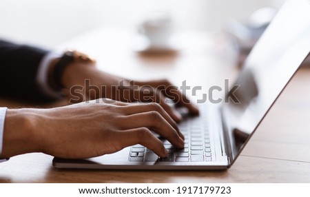 Selective focus on male hands typing on laptop keyboard, cropped, side view. African american businessman sending emails to clients or assistant. Modern technologies and business concept Royalty-Free Stock Photo #1917179723