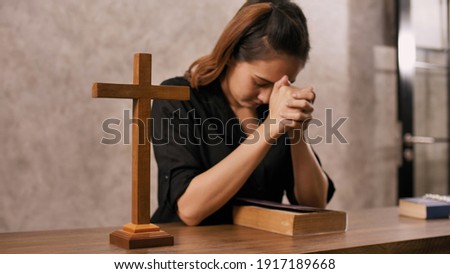 A young Asian Christian woman praying to Jesus Christ in a church.