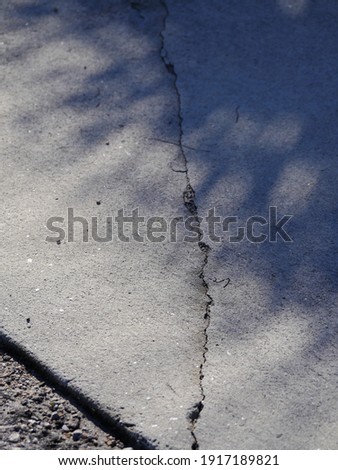 Cracks in concrete driveway, sunken areas caused by heavy equipment or settling Royalty-Free Stock Photo #1917189821