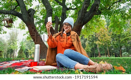 smiling woman touching face while taking selfie during picnic in park