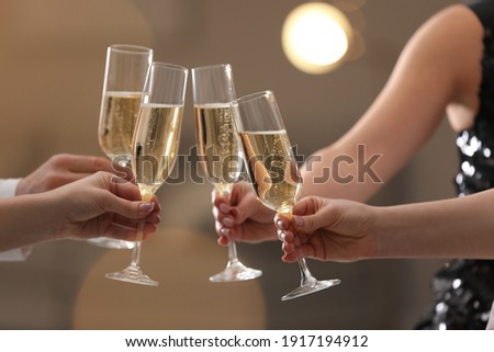 People clinking glasses of champagne against blurred background, closeup. Bokeh effect Royalty-Free Stock Photo #1917194912