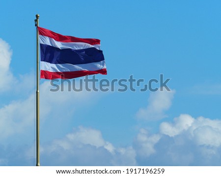 Thailand national flag waving in the sky with white clouds