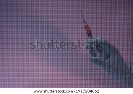 Beautiful hand holding creative syringe with red vaccine in the neon light.  Macro  photography view. Close-up of pixel.