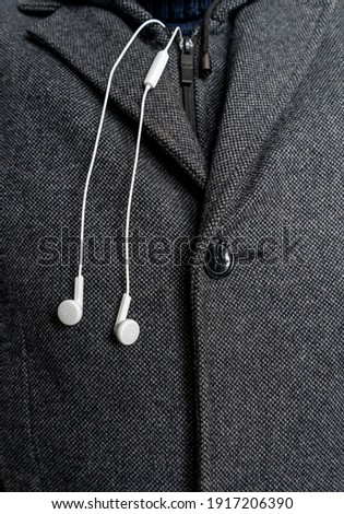 white headphones on the background of a man's coat close up.