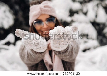 A girl in a sweater and glasses in winter in a snow-covered forest.