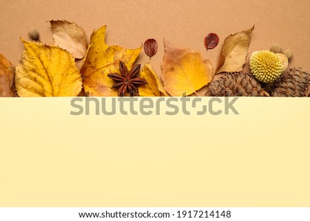 Flat lay composition with autumn leaves and blank card on beige background, space for text