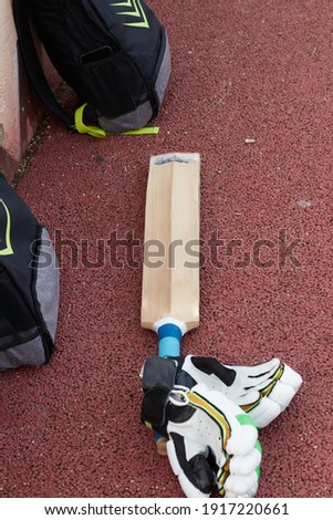Cricket bat and gloves next to a player's backpack