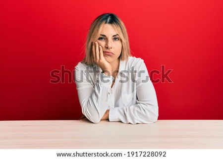 Young caucasian woman wearing casual clothes sitting on the table thinking looking tired and bored with depression problems with crossed arms. 