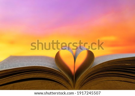 Heart from a old book page against a beautiful pinky sunset or sunrise Royalty-Free Stock Photo #1917245507