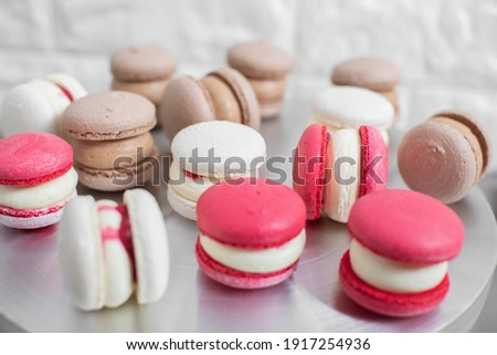 cooking, confectionery and baking concept - colorful red, white and caramel macarons on table