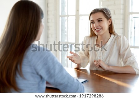 Smiling confident beautiful young woman involved in conversation with hr manager at meeting. Happy millennial female job seeker making self-presentation to employer, good first impression concept. Royalty-Free Stock Photo #1917298286