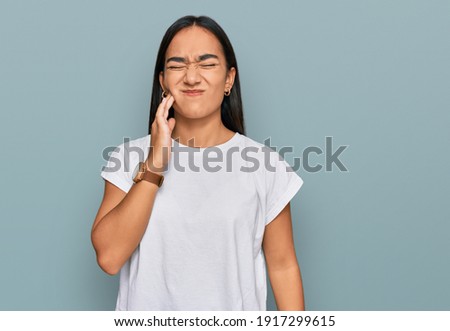 Young asian woman wearing casual white t shirt touching mouth with hand with painful expression because of toothache or dental illness on teeth. dentist  Royalty-Free Stock Photo #1917299615