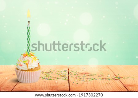 A colorful  birthday cupcake with a colored candle