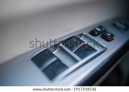 Close-up of four window switches and locks on car door. Several buttons on gray plastic door, with the word Auto in one of them. Vehicle interiors