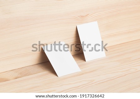 Two business cards leaning against wooden board. Clean and minimalist mock up.